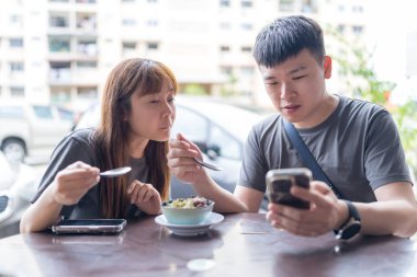 30 'lu yaşlarda Çinli Malezyalı bir çift Kuala Lumpur, Malezya' da turistler arasında popüler olan ünlü bir dükkanda Durian yerken sohbet ediyorlar..