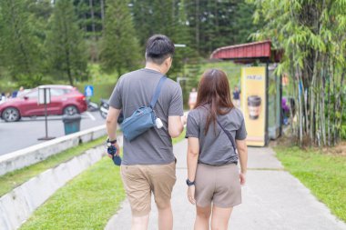 30 'lu yaşlarında Çinli bir çift, Malezya' nın Kuala Lumpur kentindeki yemyeşil, su dolu bir parkta birlikte yürüyorlar..
