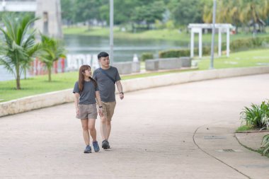 30 'lu yaşlarında Çinli bir çift, Malezya' nın Kuala Lumpur kentindeki yemyeşil, su dolu bir parkta birlikte yürüyorlar..
