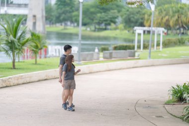 30 'lu yaşlarında Çinli bir çift, Malezya' nın Kuala Lumpur kentindeki yemyeşil, su dolu bir parkta birlikte yürüyorlar..