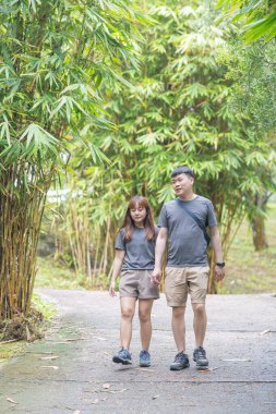 30 'lu yaşlarında Çinli bir çift, Malezya' nın Kuala Lumpur kentindeki yemyeşil, su dolu bir parkta birlikte yürüyorlar..