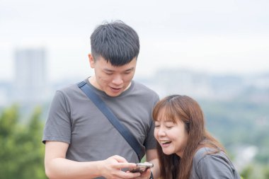 30 'lu yaşlarında Çinli bir çift, Malezya' nın Kuala Lumpur kentindeki yemyeşil, su dolu bir parkta birlikte yürüyorlar..