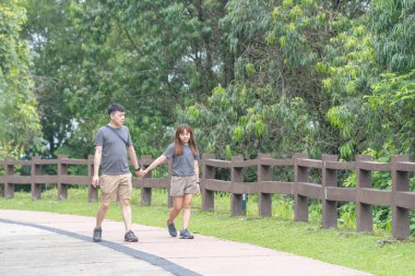 30 'lu yaşlarında Çinli bir çift, Malezya' nın Kuala Lumpur kentindeki yemyeşil, su dolu bir parkta birlikte yürüyorlar..
