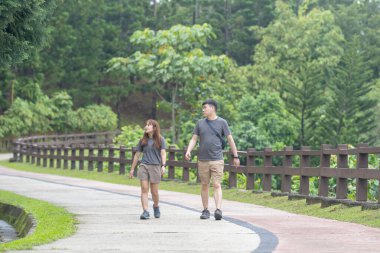 30 'lu yaşlarında Çinli bir çift, Malezya' nın Kuala Lumpur kentindeki yemyeşil, su dolu bir parkta birlikte yürüyorlar..