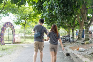 30 'lu yaşlarında Çinli bir çift, Malezya' nın Kuala Lumpur kentindeki yemyeşil, su dolu bir parkta birlikte yürüyorlar..