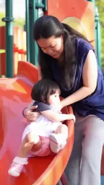 Malezyalı 30 'lu ve 1 yaşındaki Çinli anne babalar, Malezya' nın başkenti Kuala Lumpur 'da serin bir Haziran sabahı salıncaklar ve tahterevalliler üzerinde mutlu bir şekilde oynuyorlar..