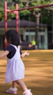 Çinli anne-babalar 30 'lu ve 1 yaşındaki kızlarıyla KLCC Parkı' nda salıncaklar ve tahterevallilerle mutlu bir şekilde oynuyorlar. Haziran sabahı Malezya 'nın başkenti Kuala Lumpur' da..