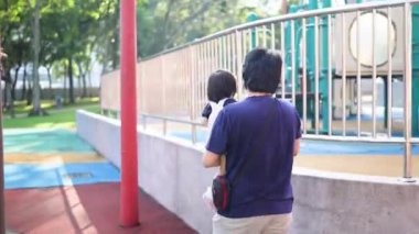Malezyalı 30 'lu ve 1 yaşındaki Çinli ebeveynler, Malezya' nın başkenti Kuala Lumpur 'da Haziran sabahı KLCC Parkı' nda salıncak ve tahterevallilerle mutlu bir şekilde oynuyorlar..