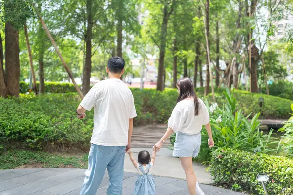 stock image A 1 year old Taiwanese girl walking hand in hand with her parents, a man and woman in their 20s, on a hot sunny day in the streets of Taichung City, Taiwan, in September.