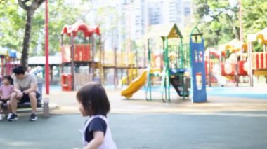 Malezyalı 30 'lu ve 1 yaşındaki Çinli ebeveynler, Malezya' nın başkenti Kuala Lumpur 'da Haziran sabahı KLCC Parkı' nda salıncak ve tahterevallilerle mutlu bir şekilde oynuyorlar..