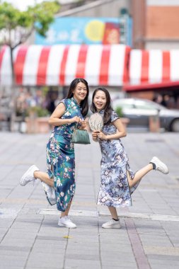 30 'lu yaşlarda, geleneksel Çin kıyafetleri giyen iki Tayvanlı kadın Eylül ayında Tayvan' ın Taipei şehrindeki Dihua Caddesi 'nde eğleniyorlar..