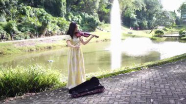 20 'li yaşlarda, sarı elbiseli Çinli bir kadın Malezya' nın Kuala Lumpur yakınlarındaki Bukit Jalil 'deki büyük doğa dolu bir parkın ormanına bakıyor. (Ağır çekim video)