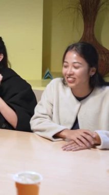 Tayvanlı 20 'li yaşlarda genç bir erkek ve kadın üniversite öğrencisi, Hintli bir kadınla birlikte Taipei City Dikey Bölgesi Da' an Üniversitesi 'nin kafeteryasında sohbet ediyorlar.