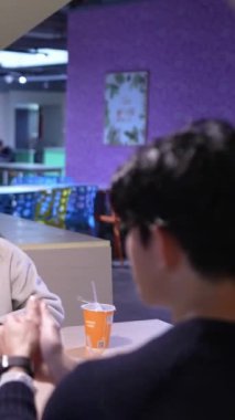 Tayvanlı 20 'li yaşlarda genç bir erkek ve kadın üniversite öğrencisi, Hintli bir kadınla birlikte Taipei City Dikey Bölgesi Da' an Üniversitesi 'nin kafeteryasında sohbet ediyorlar.