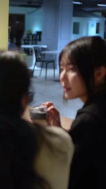 Tayvanlı 20 'li yaşlarda genç bir erkek ve kadın üniversite öğrencisi, Hintli bir kadınla birlikte Taipei City Dikey Bölgesi Da' an Üniversitesi 'nin kafeteryasında sohbet ediyorlar.