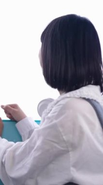 20 'li yaşlarında Tayvanlı genç bir kadın Tayvan' ın Taipei şehrindeki Shilin semtinde bir lunaparkta fotoğraf çekiyor ve müzik dinliyor. Dikey video.