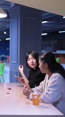 Tayvanlı 20 'li yaşlarda genç bir erkek ve kadın üniversite öğrencisi, Hintli bir kadınla birlikte Taipei City Dikey Bölgesi Da' an Üniversitesi 'nin kafeteryasında sohbet ediyorlar.