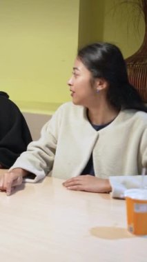 Tayvanlı 20 'li yaşlarda genç bir erkek ve kadın üniversite öğrencisi, Hintli bir kadınla birlikte Taipei City Dikey Bölgesi Da' an Üniversitesi 'nin kafeteryasında sohbet ediyorlar.