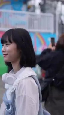 Tayvan 'ın Taipei şehrindeki Shilin Bölgesi' nde bir lunaparkta 20 'li yaşlarda genç bir Tayvanlı kadın akşam vakti yürüyor. Dikey video.