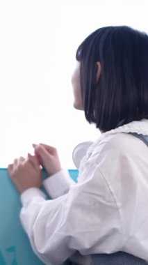 20 'li yaşlarında Tayvanlı genç bir kadın Tayvan' ın Taipei şehrindeki Shilin semtindeki lunaparkta fotoğraf çekiyor ve müzik dinliyor. Dikey yavaş çekim videosu.