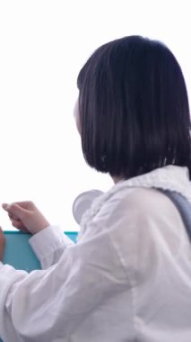 20 'li yaşlarında Tayvanlı genç bir kadın Tayvan' ın Taipei şehrindeki Shilin semtindeki lunaparkta fotoğraf çekiyor ve müzik dinliyor. Dikey yavaş çekim videosu.