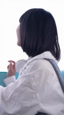 20 'li yaşlarında Tayvanlı genç bir kadın Tayvan' ın Taipei şehrindeki Shilin semtindeki lunaparkta fotoğraf çekiyor ve müzik dinliyor. Dikey yavaş çekim videosu.