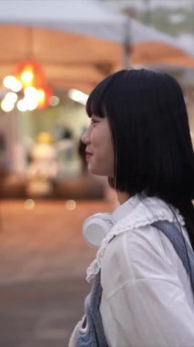 Tayvan 'ın Taipei şehrindeki Shilin Bölgesi' nde bir lunaparkta 20 'li yaşlarda genç bir Tayvanlı kadın akşam vakti yürüyor. Dikey yavaş çekim videosu.