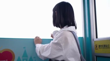 20 'li yaşlarında Tayvanlı genç bir kadın Tayvan' ın Taipei şehrindeki Shilin semtinde bir lunaparkta fotoğraf çekiyor ve müzik dinliyor. Yavaş çekim videosu.