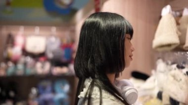 Tayvan 'ın Taipei şehrindeki Shilin semtinde bir lunaparkta buluşurken 20' li yaşlarında genç bir Tayvanlı kadın hediyelik eşya dükkanından alışveriş yapıyor. Yavaş çekim videosu.