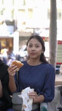 Tayvanlı 20 'li yaşlarda erkek ve bayan öğrenciler ve Tayvan' ın Taipei şehrinde halka açık bir yolda waffle yiyip sohbet eden Hintli bir kadın. Dikey.