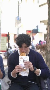 Tayvanlı 20 'li yaşlarda erkek ve bayan öğrenciler ve Tayvan' ın Taipei şehrinde halka açık bir yolda waffle yiyip sohbet eden Hintli bir kadın. Dikey.