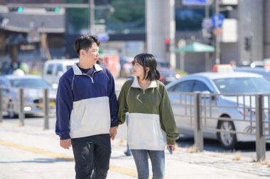 Bir çift, 30 'lu yaşlarda Koreli bir adam ve 20' li yaşlarda eşofman giyen bir kadın, Seul, Güney Kore 'de halka açık bir yolda öğleden sonra gezintisi yapıyorlar..