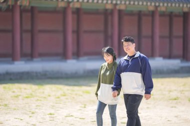 Koreli bir çift, 30 'lu yaşlarda bir adam ve 20' li yaşlarda bir kadın, Güney Kore 'nin Seul şehrindeki tarihi bir binada uyumlu bir şekilde yürüyorlar..