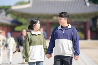 Koreli bir çift, 30 'lu yaşlarda bir adam ve 20' li yaşlarda bir kadın, Güney Kore 'nin Seul şehrindeki tarihi bir binada uyumlu bir şekilde yürüyorlar..