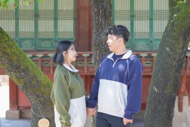 Koreli bir çift, 30 'lu yaşlarda bir adam ve 20' li yaşlarda bir kadın, Güney Kore 'nin Seul şehrindeki tarihi bir binada uyumlu bir şekilde yürüyorlar..