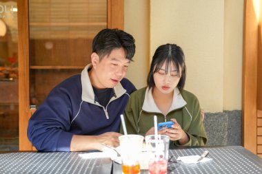 A couple, a Korean man in his 30s and a woman in her 20s, wear tracksuits and enjoy an afternoon at a nice Western-style cafe in Seoul, South Korea. clipart