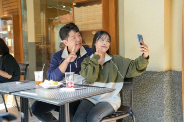 30 'lu yaşlarda Koreli bir çift ve 20' li yaşlarda bir kadın eşofman giyip Seul, Güney Kore 'de güzel bir Batı tarzı kafede güzel bir öğleden sonra geçiriyorlar..