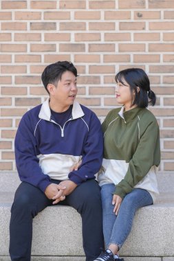 30 'larında Koreli bir erkek ve 20' li yaşlarında eşofman giyen bir kadın zamanlarını Güney Kore, Seul 'deki tarihi bir binada mutlu bir şekilde geçiriyorlar..