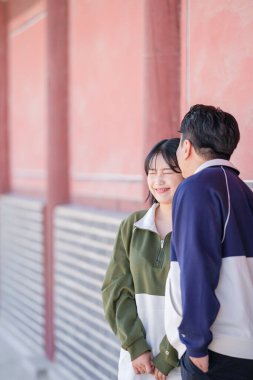 A sporty Korean couple, a man in his 30s and a woman in her 20s, wearing tracksuits, spends their time together happily at a historical building in Seoul, South Korea. clipart