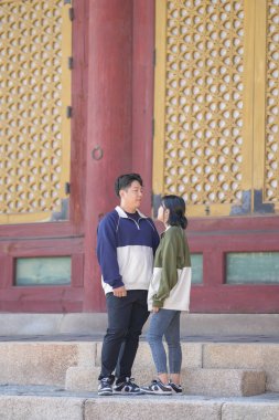 30 'larında Koreli bir erkek ve 20' li yaşlarında eşofman giyen bir kadın zamanlarını Güney Kore, Seul 'deki tarihi bir binada mutlu bir şekilde geçiriyorlar..