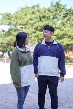 30 'larında Koreli bir erkek ve 20' li yaşlarında eşofman giyen bir kadın zamanlarını Güney Kore, Seul 'deki tarihi bir binada mutlu bir şekilde geçiriyorlar..