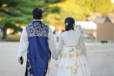 Koreli bir çift, 30 'lu yaşlarda bir adam ve 20' li yaşlarda bir kadın, Güney Kore, Seul 'de Hanbok giyerek halka açık bir yolda uyumlu bir şekilde yürüyorlar..
