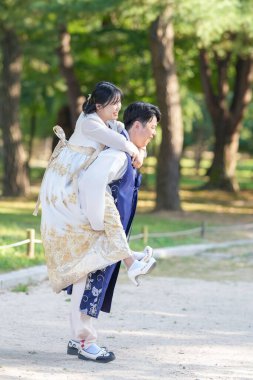 Koreli bir çift, 30 'lu yaşlarda bir adam ve 20' li yaşlarında bir kadın, Güney Kore, Seul 'de yeşil ağaçlarla çevrili bir parkta Hanbok giyip birbirlerine sarılıyorlar..