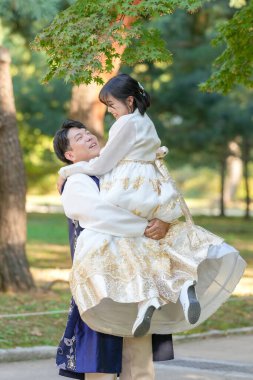 Koreli bir çift, 30 'lu yaşlarda bir adam ve 20' li yaşlarında bir kadın, Güney Kore, Seul 'de yeşil ağaçlarla çevrili bir parkta Hanbok giyip birbirlerine sarılıyorlar..