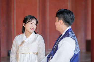 Koreli bir çift, 30 'lu yaşlarda bir adam ve 20' li yaşlarda bir kadın, mutlu bir şekilde Hanbok giyiyorlar ve Güney Kore, Seul 'de tarihi bir binada oturuyorlar..