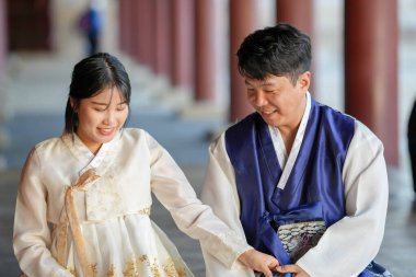 Koreli bir çift, 30 'lu yaşlarda bir adam ve 20' li yaşlarda bir kadın, mutlu bir şekilde Hanbok giyiyorlar ve Güney Kore, Seul 'de tarihi bir binada oturuyorlar..