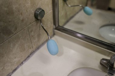 Mavi sabun makinesi lavaboda. Sabun makinesi mavi ve gümüş sapı var.