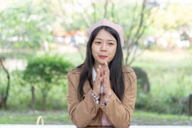 Tayvan 'ın Xinyi İlçesi' ndeki bir bankta oturan, 20 'li yaşlarda kahverengi trençkot giyen, uzun saçlı Tayvanlı bir kadın 30 Ocak 2024' te öğleyin çikolata yer..