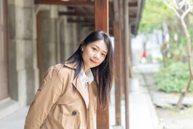 20 'li yaşlarda uzun saçlı Tayvanlı bir kadın 30 Ocak 2024' te Tayvan 'ın Xinyi ilçesindeki sazlıkların altında bej renkli bir trençkot giyiyor..