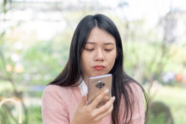 30 Ocak 2024 'te Tayvan' ın Tayvan şehrinde Xinyi İlçesi 'nde bir bankta otururken 20' li yaşlarda pembe kazak giyen uzun saçlı bir kadın akıllı telefonuyla konuşuyor..